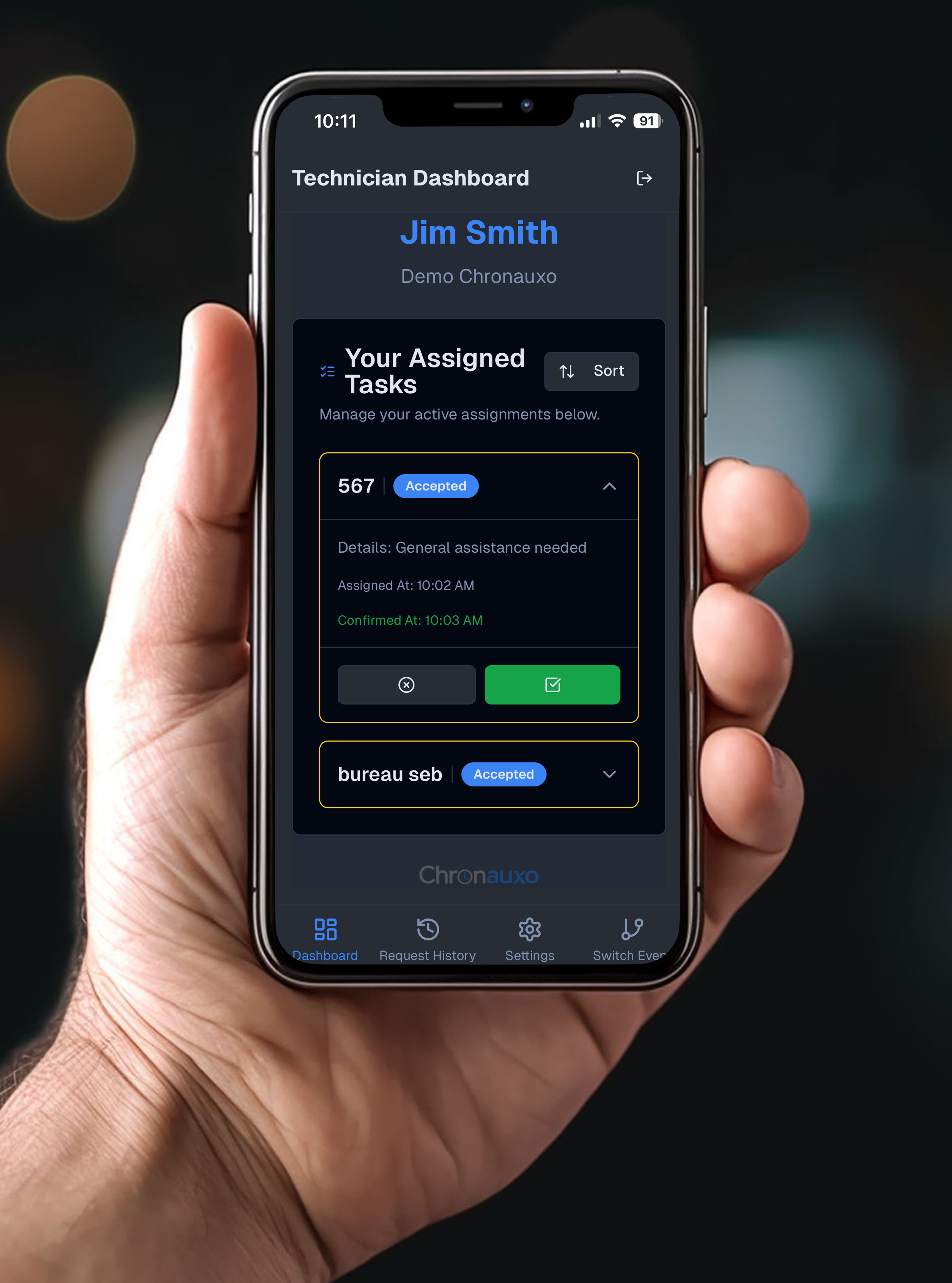 A technician holding a phone displaying the Chronauxo app.